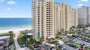 A high-rise hotel with multiple balconies, a swimming pool, and a beach view. - Beach Colony East 8D (Pensacola)