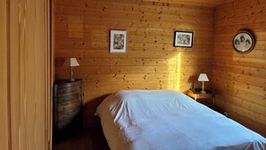Ett rum med träpanel på väggarna, en säng, två inramade tavlor och ett litet bord med en lampa.