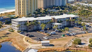 A high-rise hotel with multiple floors, a parking lot, and a view of the ocean. - Grand Caribbean West 310 (Pensacola)
