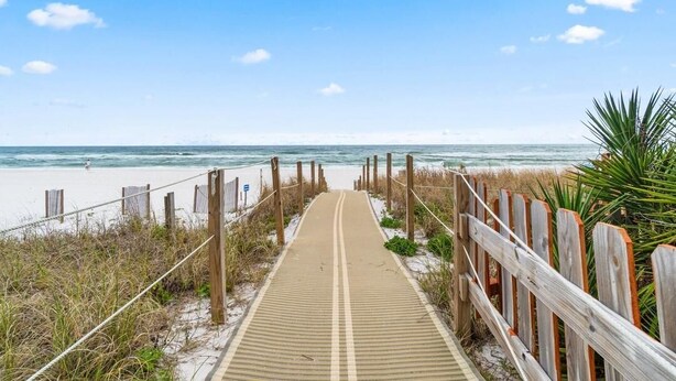 A wooden boardwalk leading to a beach with a clear sky. - Grand Caribbean West 310 (Pensacola)