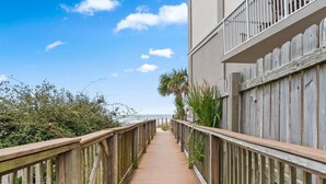 A wooden boardwalk leading to a building with a balcony. - Grand Caribbean West 310 (Pensacola)