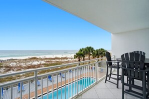 Un balcone con piscina, vista sulla spiaggia e area salotto esterna.