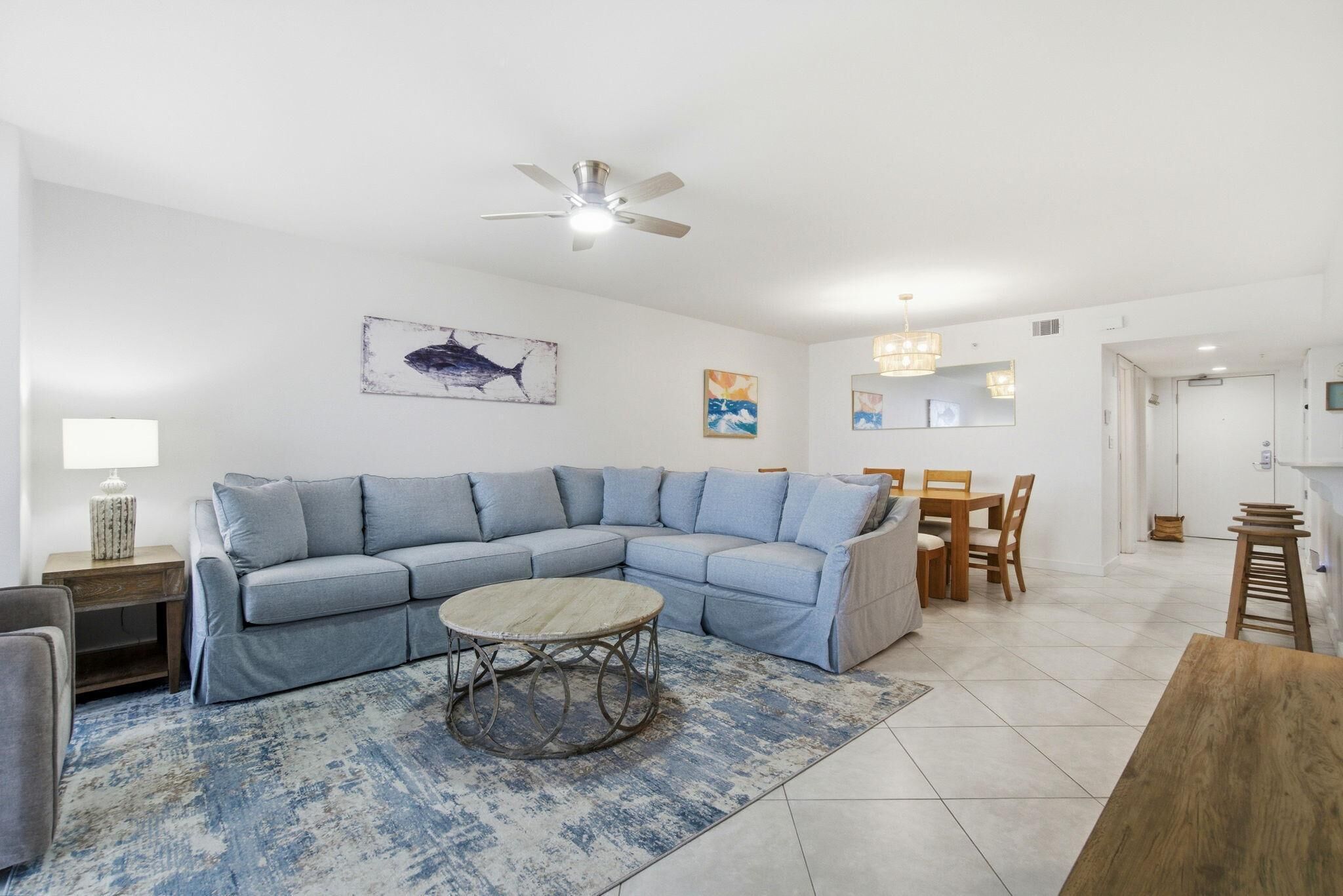 A living room with a sectional sofa, a round coffee table, and a ceiling fan.