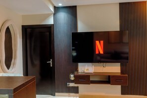 Ein modernes Wohnzimmer mit einem großen Flachbildfernseher an einer Holzwand, einer dunklen Holztür und einer eingebauten TV-Konsole mit einer Schublade.