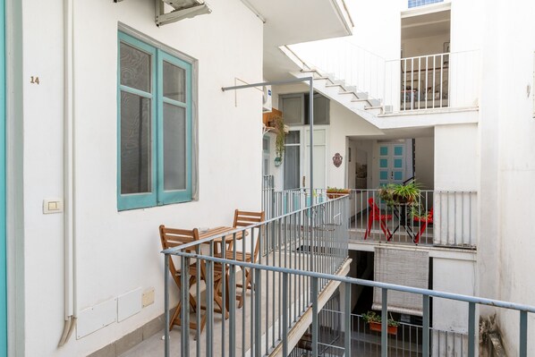 A multi-level residential building with a balcony, a staircase, and a door with a blue window. - Casa le Radici by Wonderful Italy (Syracuse)