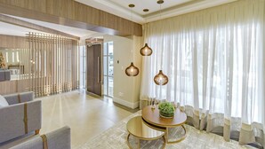 A spacious living area with a modern design, featuring a round table with a plant, a sofa, and a decorative partition. - Apartamento no Centro com 3 su tes a 400m da Praia (Balneário Camboriú)