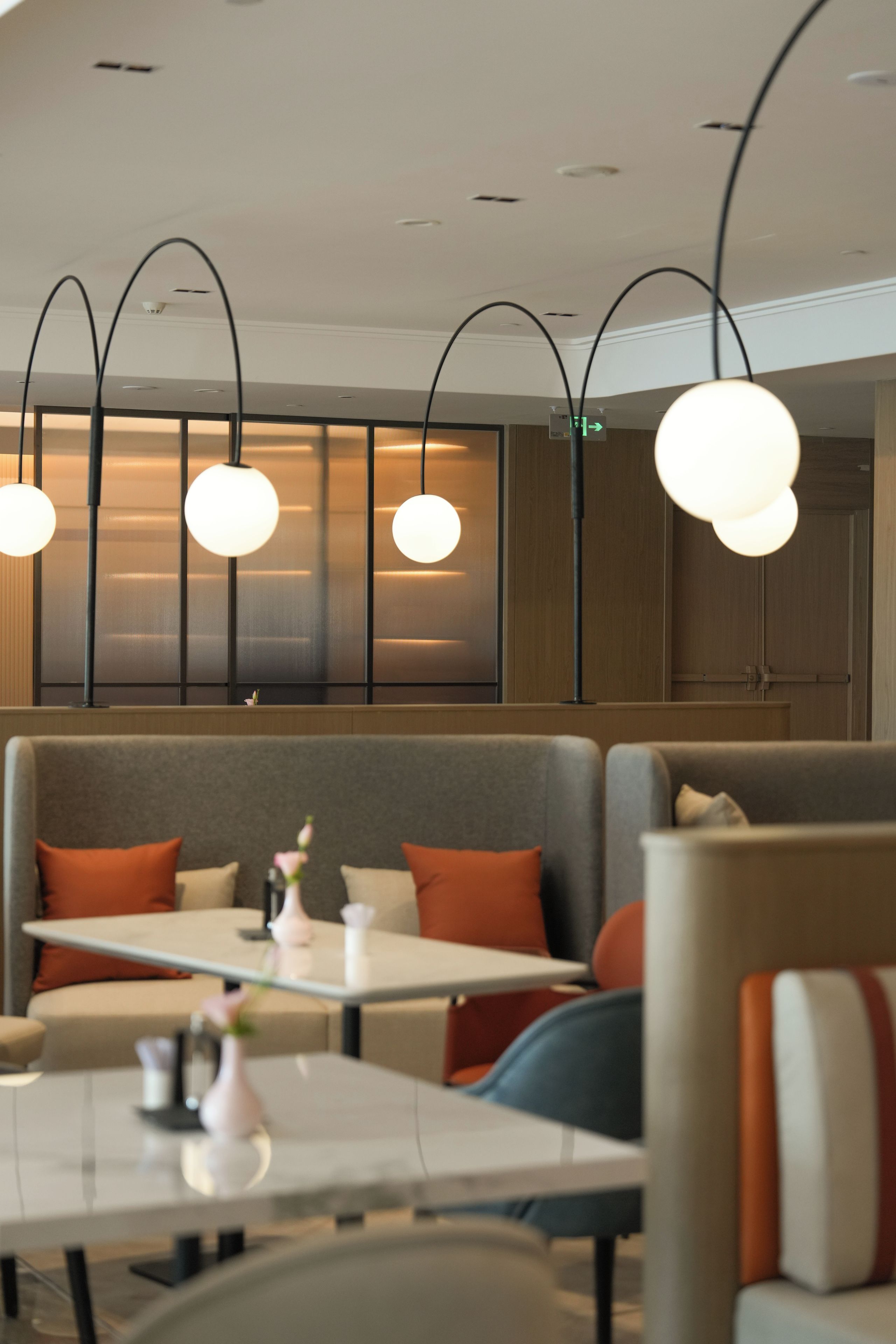 A modern dining area with booths and tables, overhead lighting, and a view of the interior.