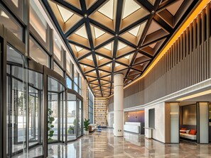 Eine geräumige Lobby mit hoher Decke, großen Fenstern und einer Rezeption.