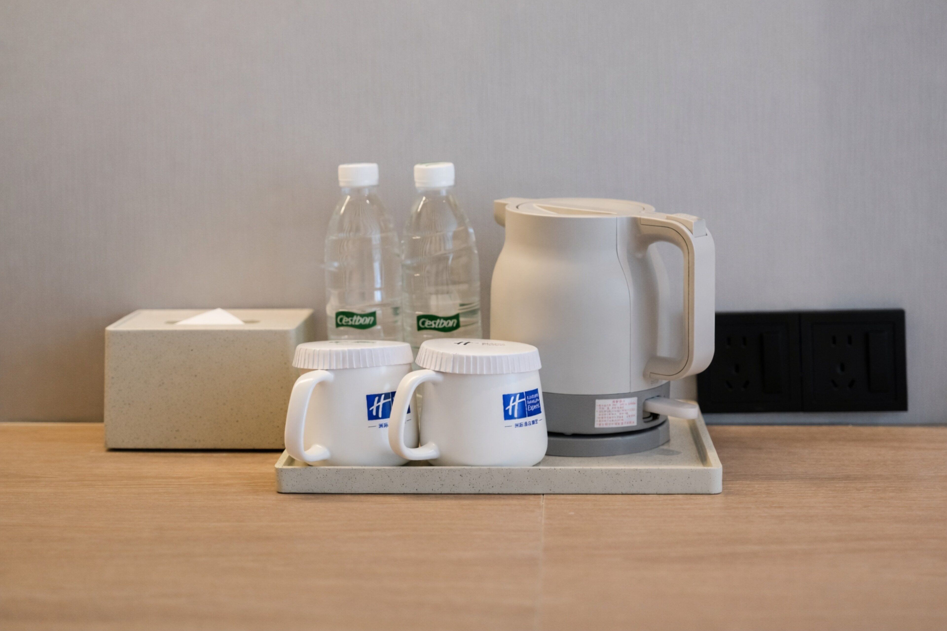 Ein Tablett mit einer Taschentuchbox, zwei Wasserflaschen und einer Kaffeemaschine.