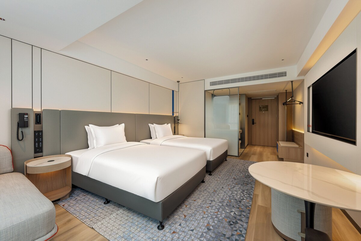 Een moderne hotelkamer met een groot bed, nachtkastje, bureau en flatscreen-tv.