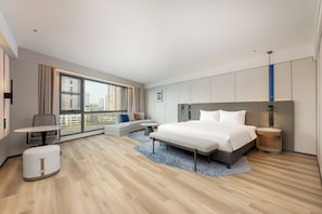 Een moderne hotelkamer met een groot bed, een bureau, een bank en uitzicht op de stad.