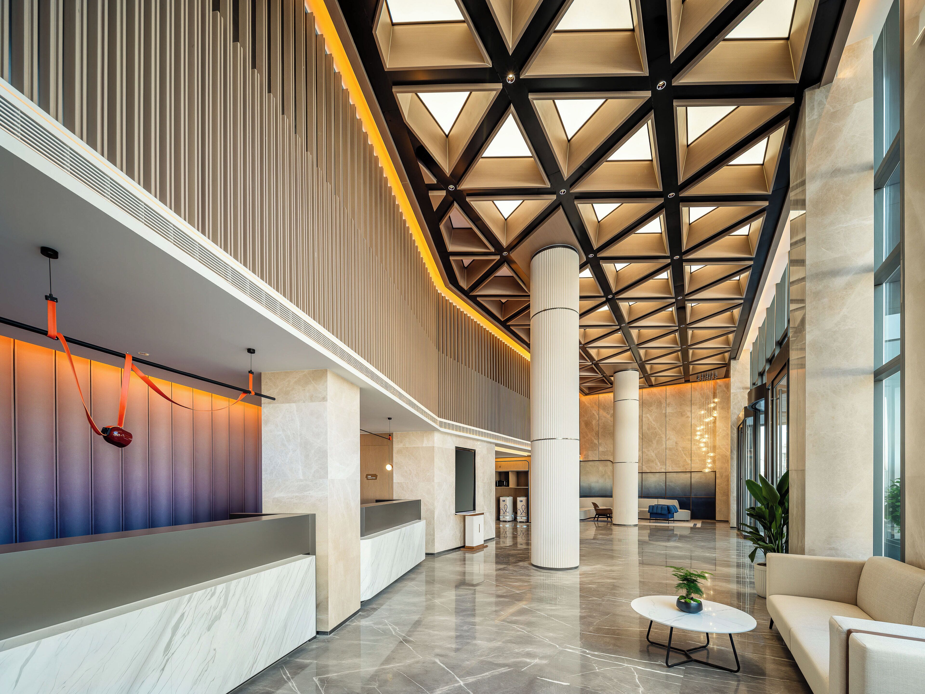 A spacious lobby with a high ceiling, large columns, and a reception desk.