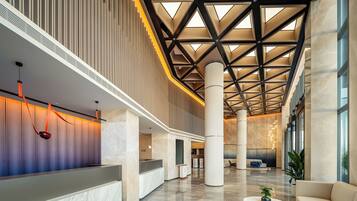 A spacious lobby with a high ceiling, large columns, and a reception desk.