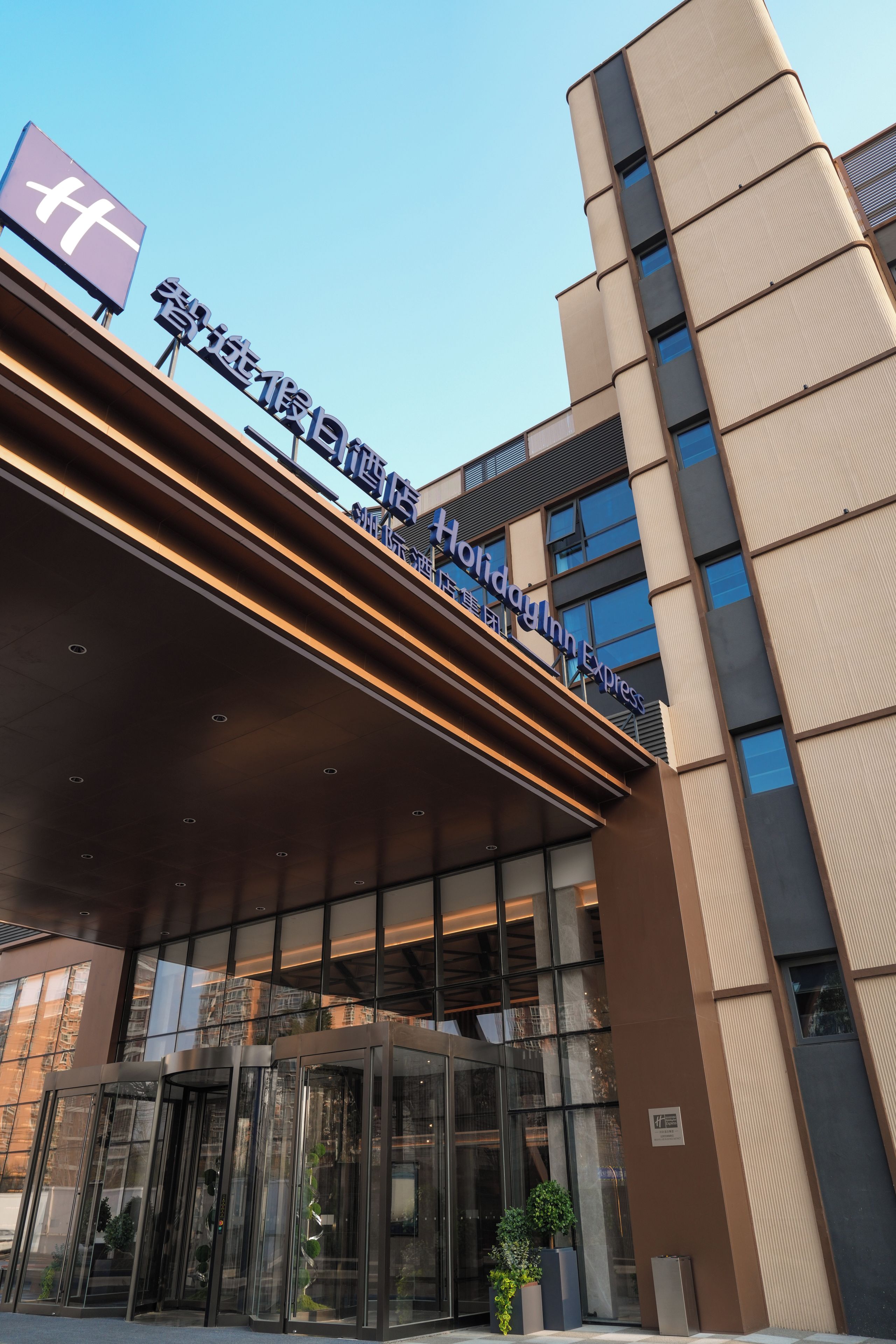A hotel entrance with a modern design, featuring a glass facade and a sign indicating it is a Holiday Inn Express.
