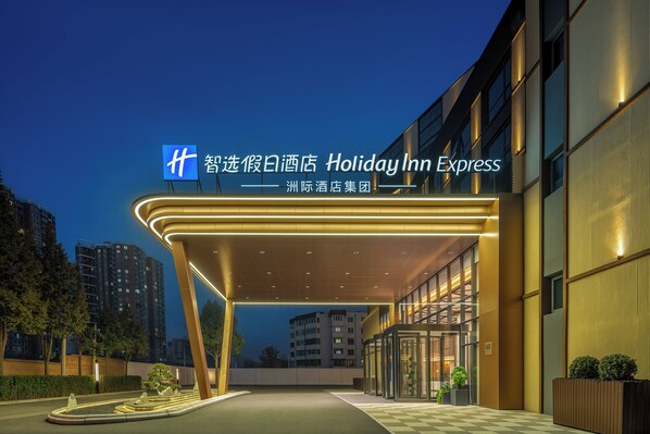L’entrée d’un hôtel Holiday Inn Express, dotée d’un design moderne, avec une passerelle couverte et une façade en verre.