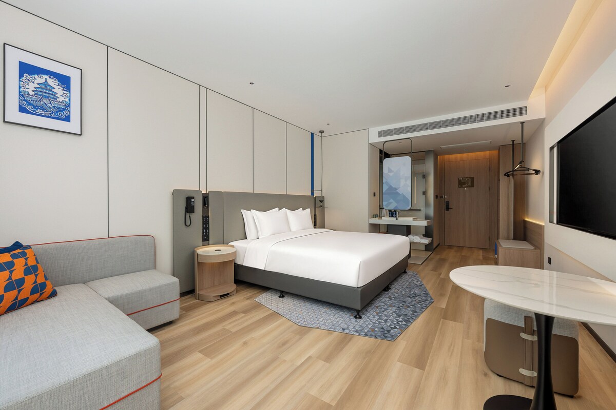 Una habitación de hotel moderna con cama, sofá, escritorio y televisor.