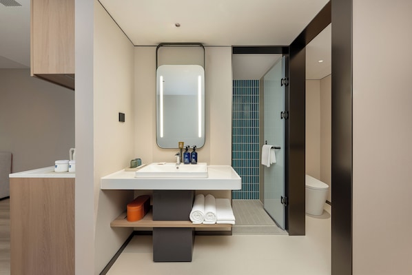 Un baño moderno con un espejo grande, lavamanos blanco y un perchero para toallas.