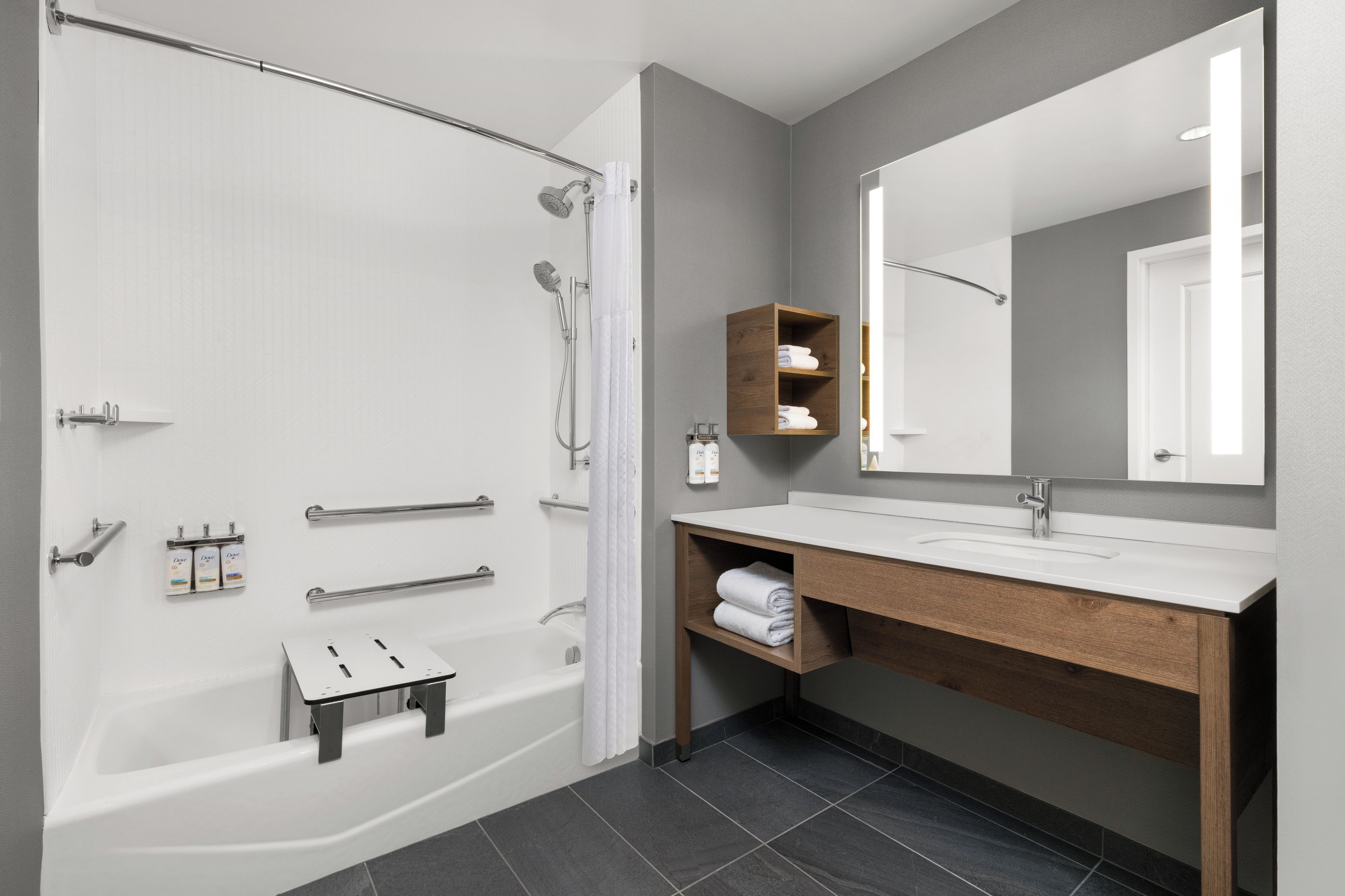 Une salle de bain moderne équipée d’une baignoire, d’une douche, d’un meuble-lavabo avec miroir et d’un porte-serviettes.