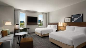 Une chambre d’hôtel avec deux lits, un bureau, une chaise, un canapé et une télévision.