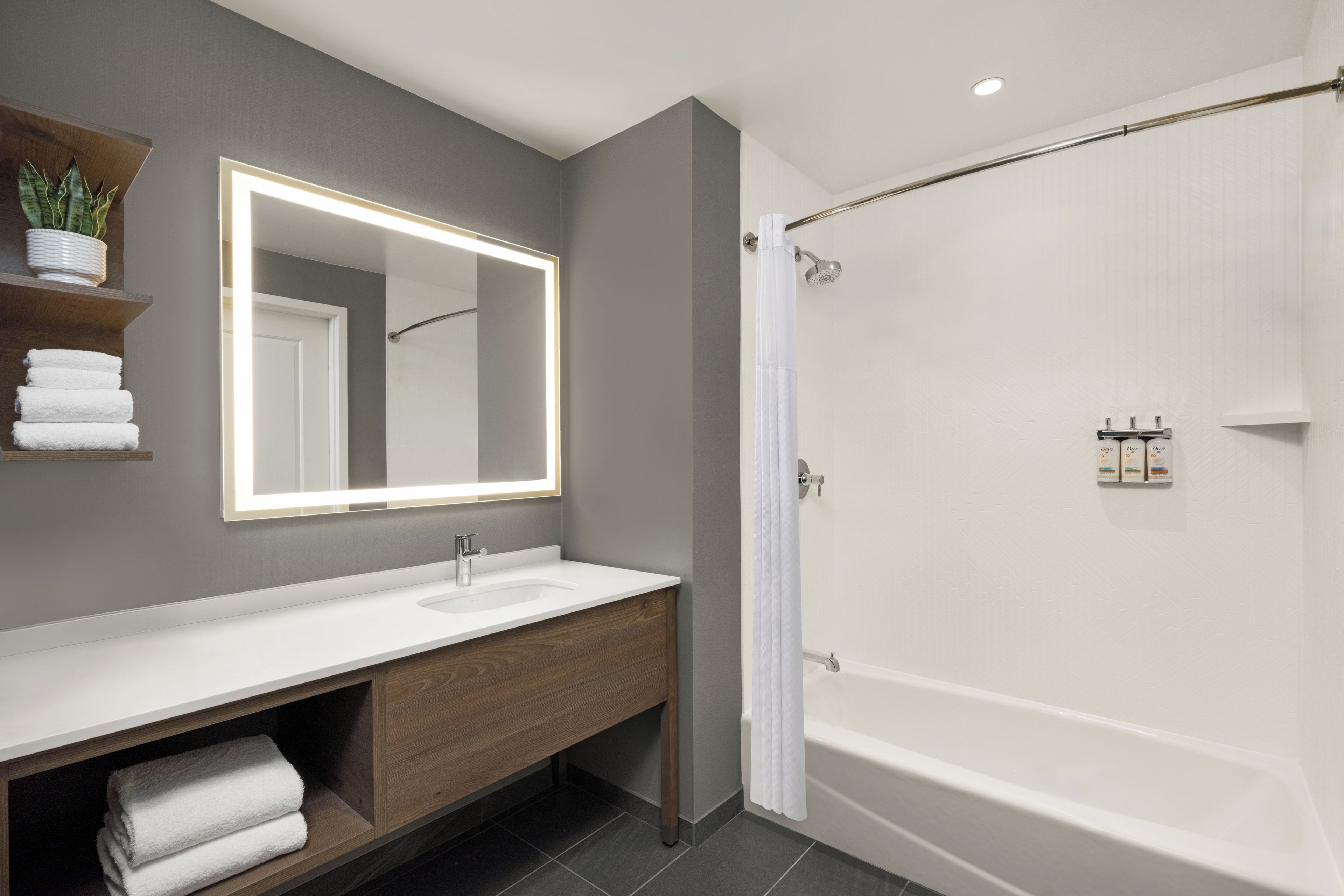 A modern bathroom with a large mirror, a bathtub, and a shower.