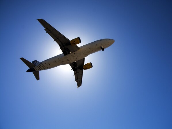 Un avión comercial volando contra un cielo azul despejado.
