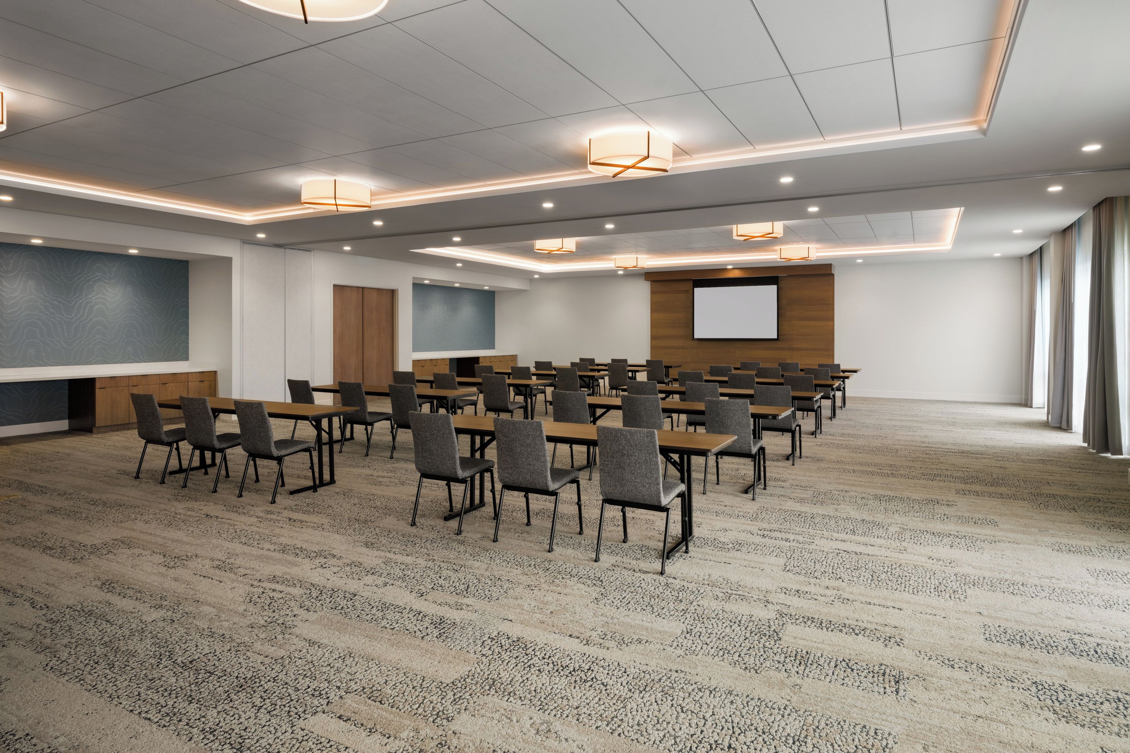 A conference room with a large screen, multiple tables, and chairs arranged for meetings.