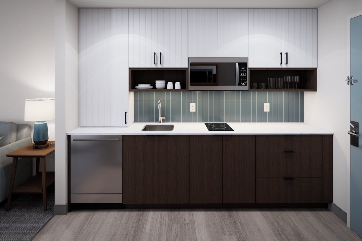 Una cocina moderna con microondas integrado, un lavamanos y armarios de madera.