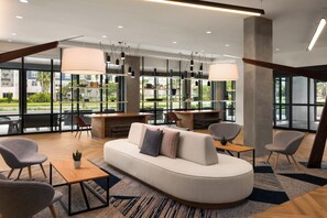 Un espace de détente moderne avec un canapé incurvé, plusieurs fauteuils, une table en bois et des luminaires suspendus.