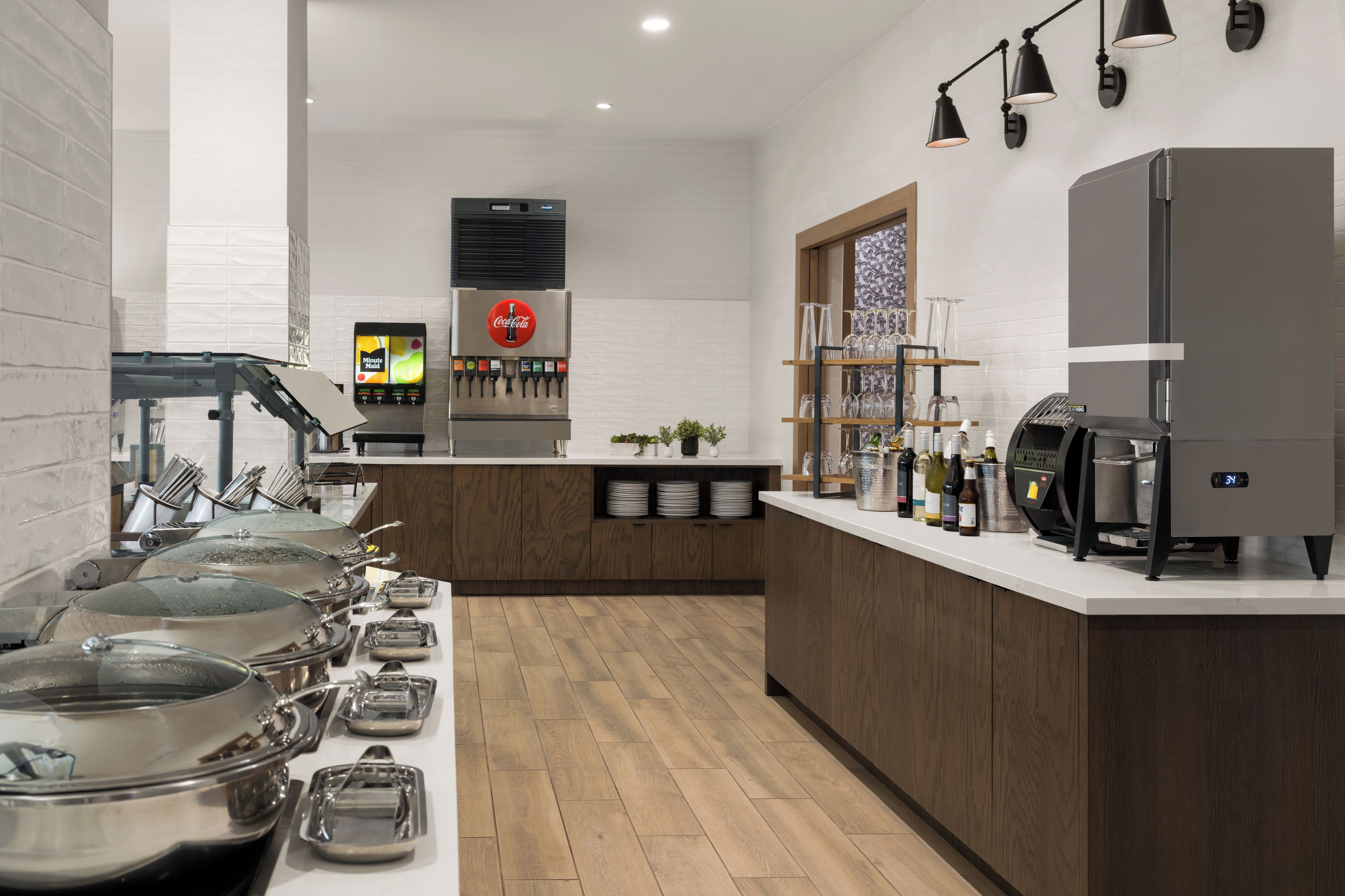 A modern kitchen with a coffee machine, a refrigerator, and a Coca-Cola dispenser.