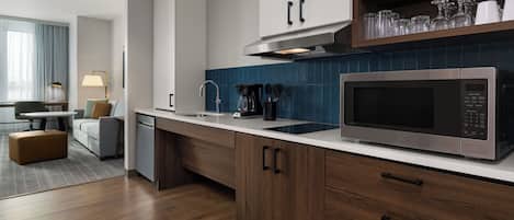 A modern kitchen with a built-in microwave, a coffee maker, and a sink.