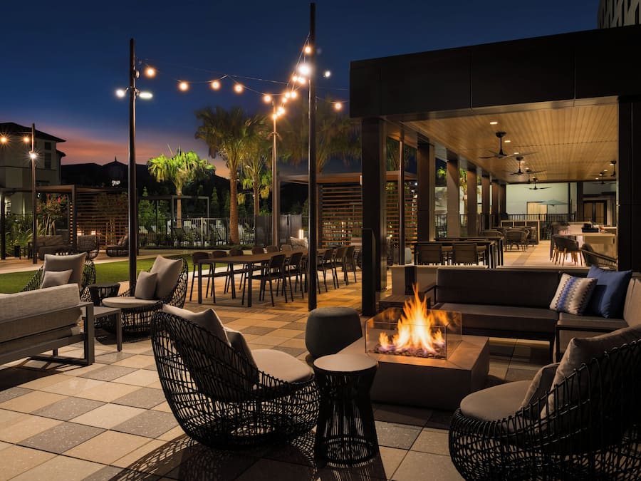 An outdoor seating area with wicker furniture, a fire feature, and string lights.
