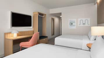 Una habitación de hotel con cama, escritorio, silla, televisor y obras de arte en la pared.