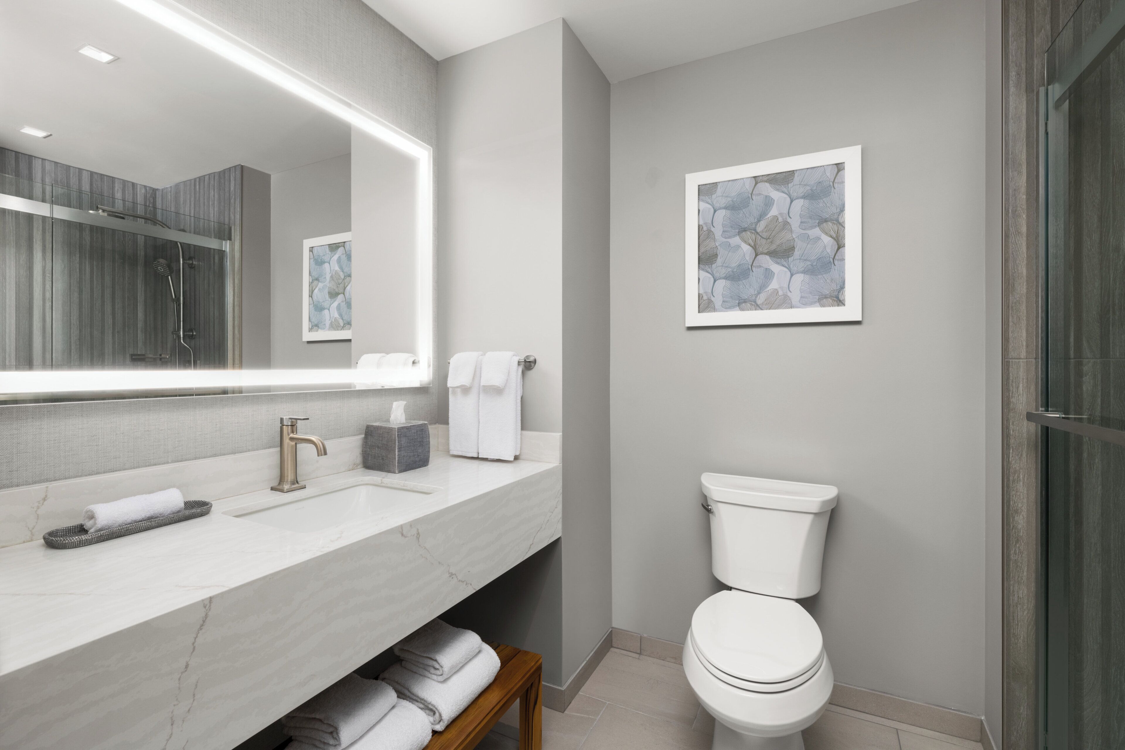 Une salle de bain moderne avec un lavabo en marbre, un grand miroir, des toilettes et un espace douche.