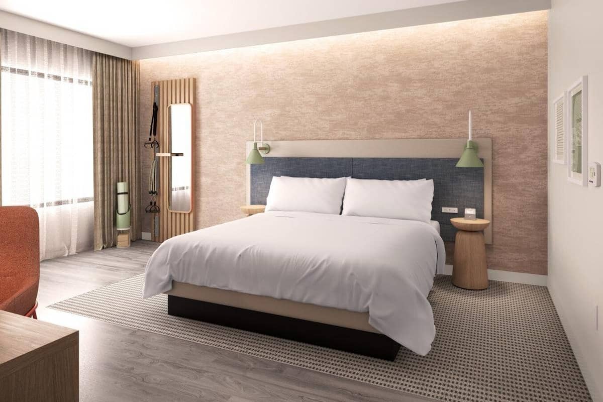 A modern hotel room with a large bed, two bedside tables, a desk, and a chair.