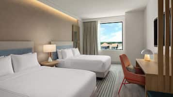 Habitación de hotel con dos camas, un escritorio, una silla, un televisor y una ventana con vistas a edificios.