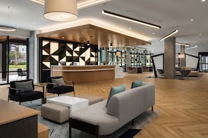 A modern lobby with a reception desk, seating area, and a view of the outdoors. - Even Hotel Orlando Universal Blvd By Ihg (Orlando)