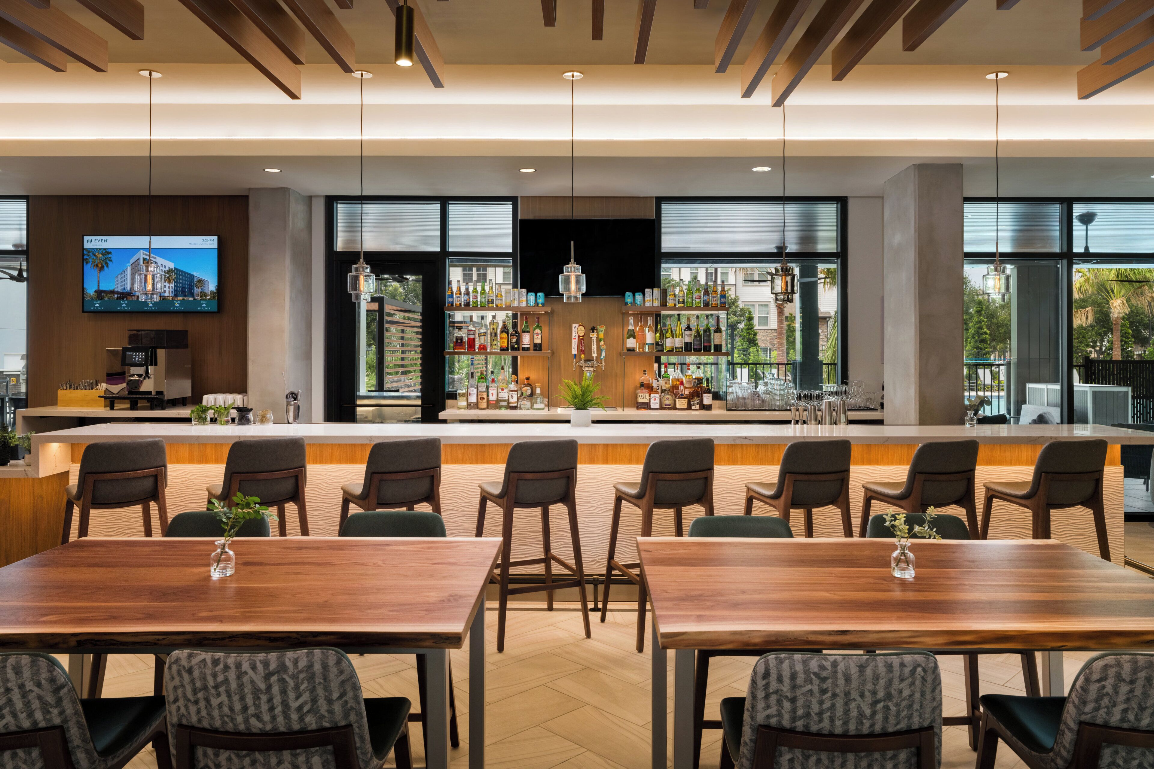 A modern bar area with multiple seating options and a large window providing a view of the cityscape.