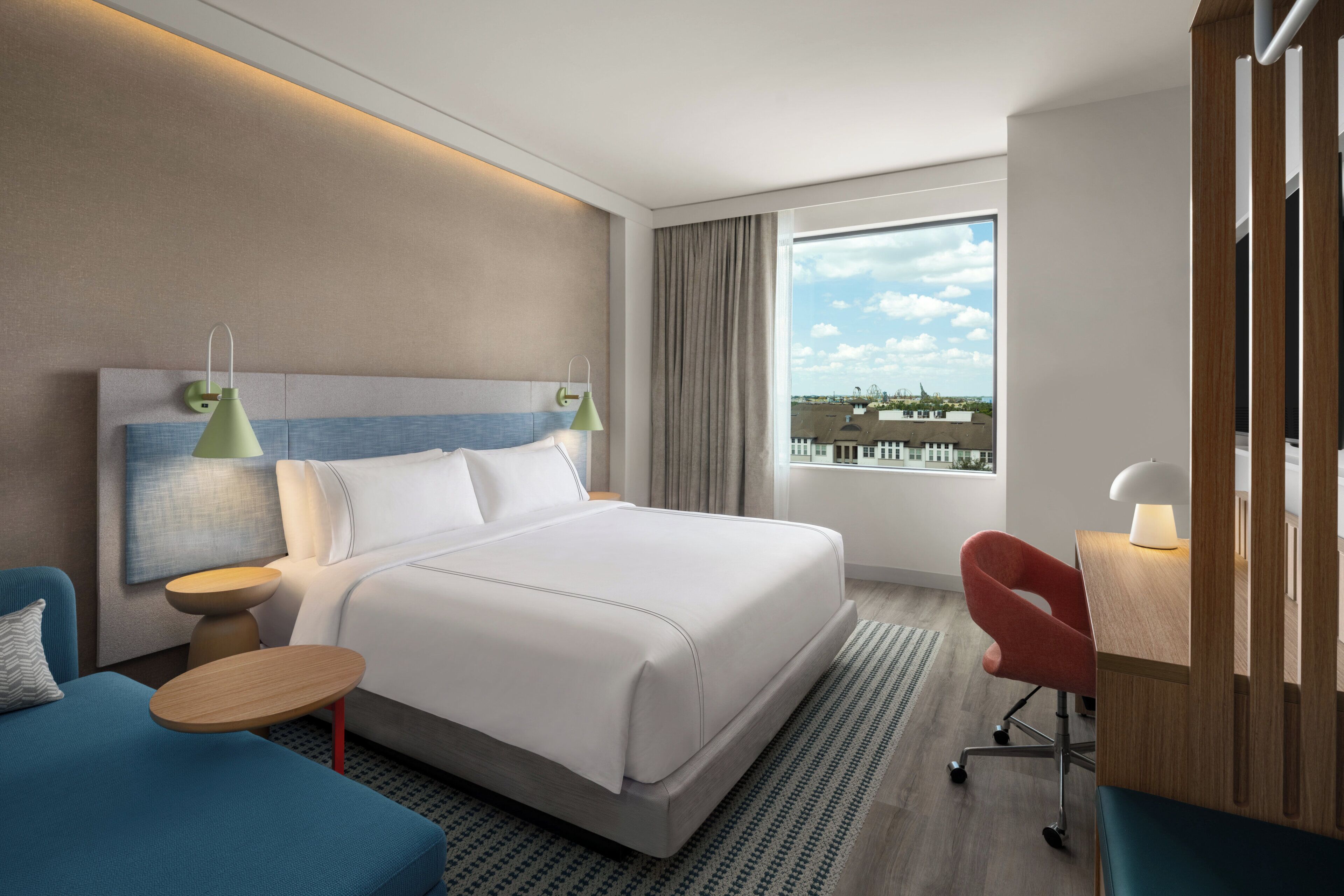 Habitación de hotel moderna con una cama grande, un escritorio, una silla y vistas a la ciudad.
