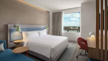 Habitación de hotel moderna con una cama grande, un escritorio, una silla y vistas a la ciudad.