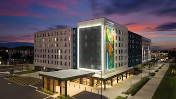 A multi-story hotel with a modern design, featuring a large illuminated sign and a landscaped courtyard.
