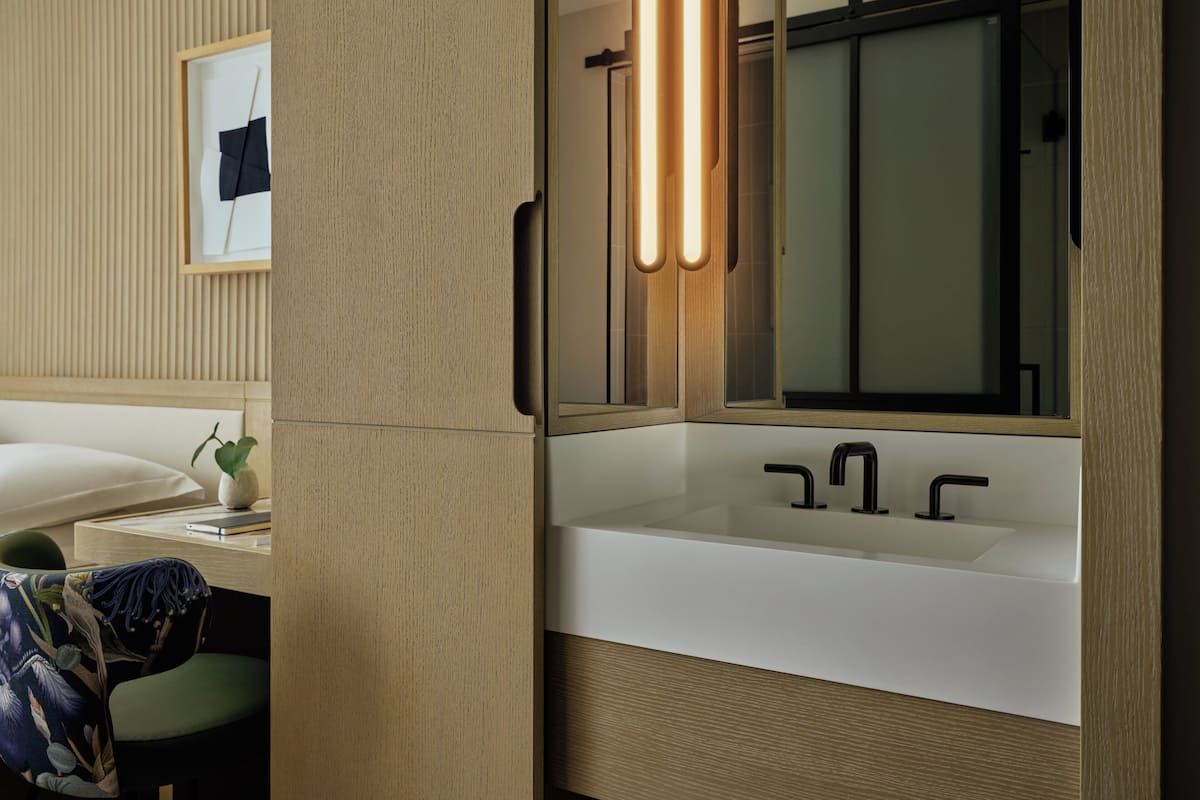 Un baño moderno con un espejo grande, un lavamanos blanco y un mueble de tocador de madera.
