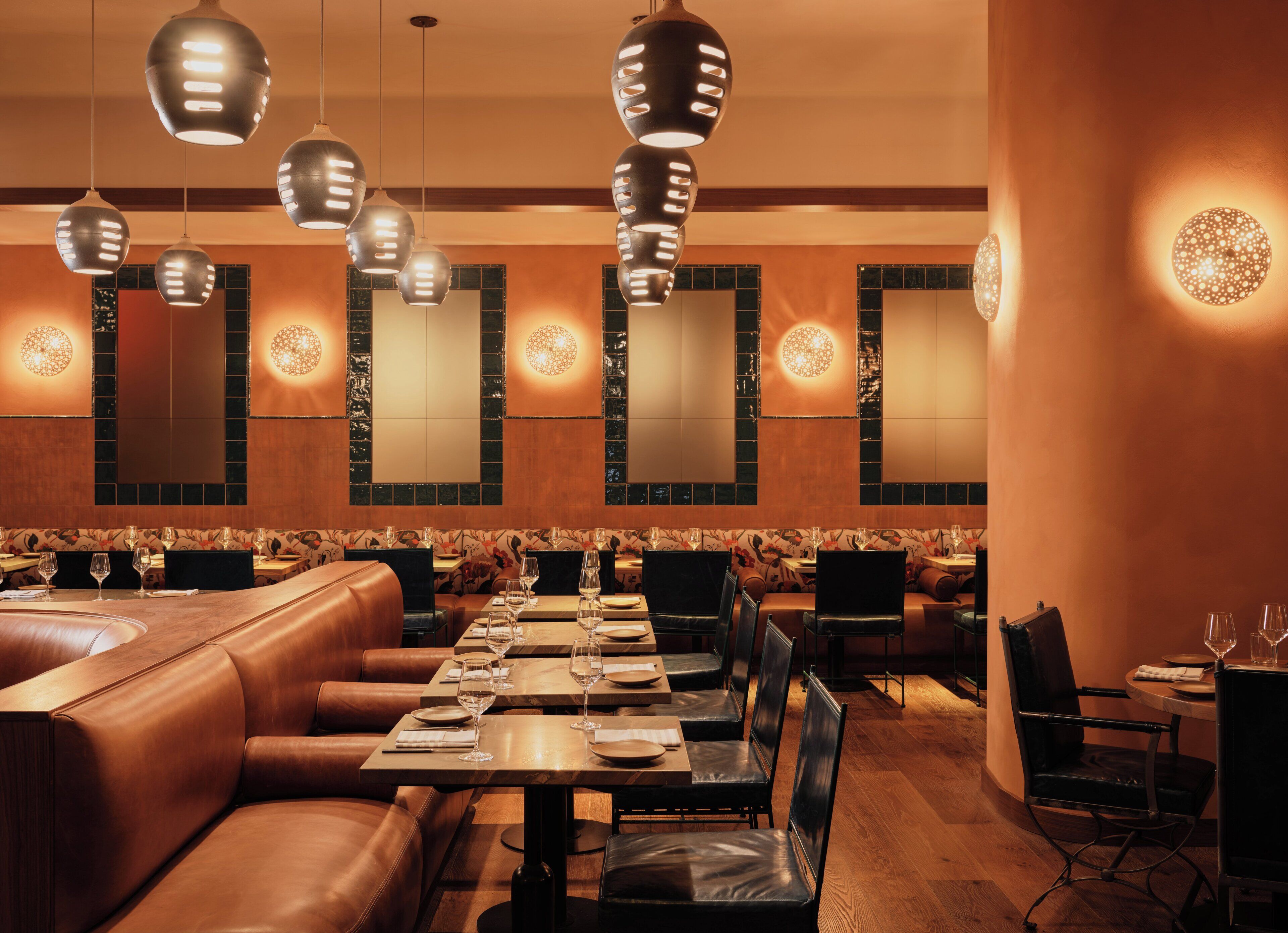 Un restaurante con cabinas de cuero, mesas de madera y lámparas colgantes.