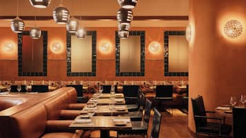 Un restaurante con cabinas de cuero, mesas de madera y lámparas colgantes.