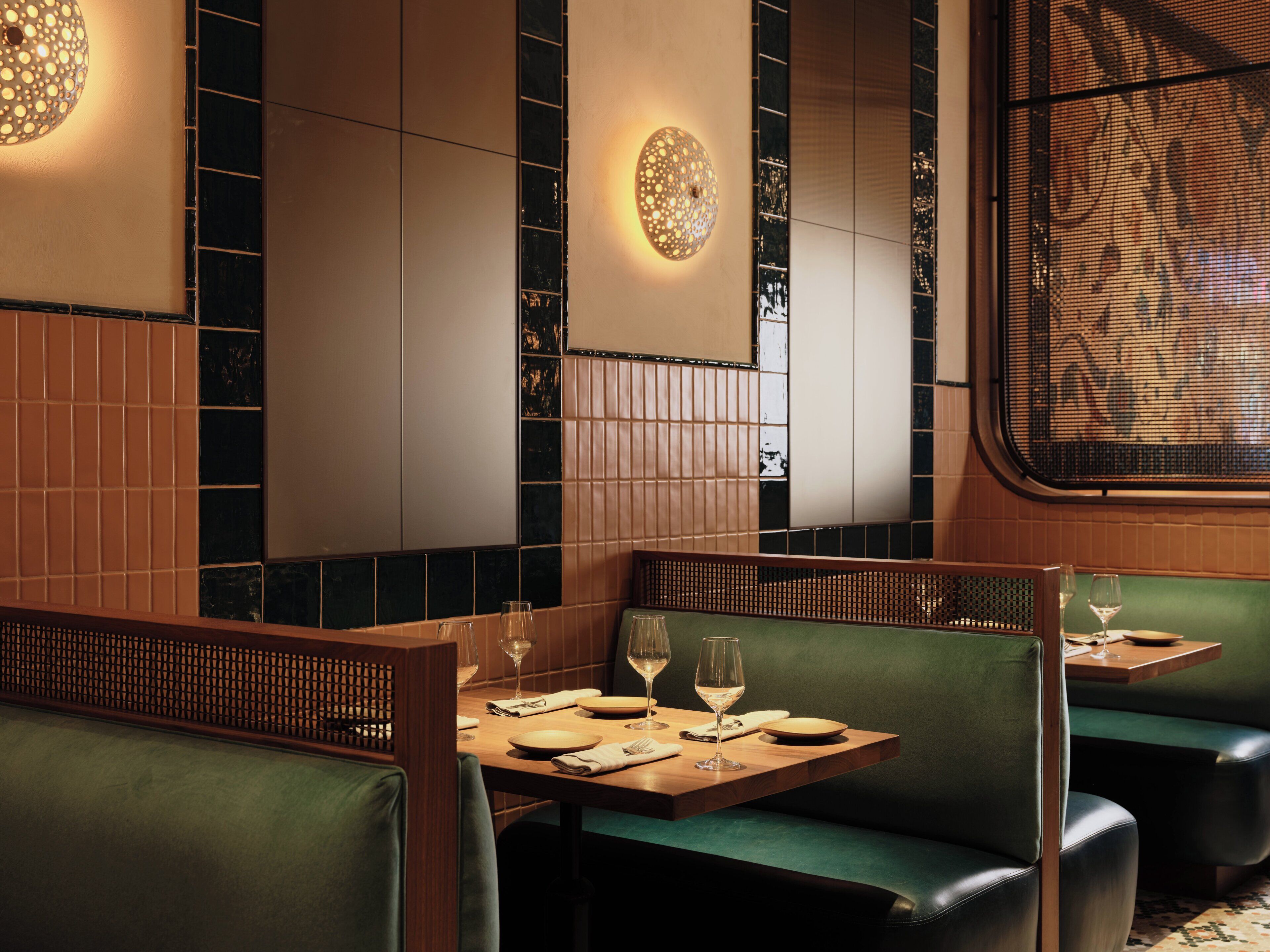 L’intérieur d’un restaurant avec des banquettes, des tables en bois et des sièges rembourrés de couleur verte.