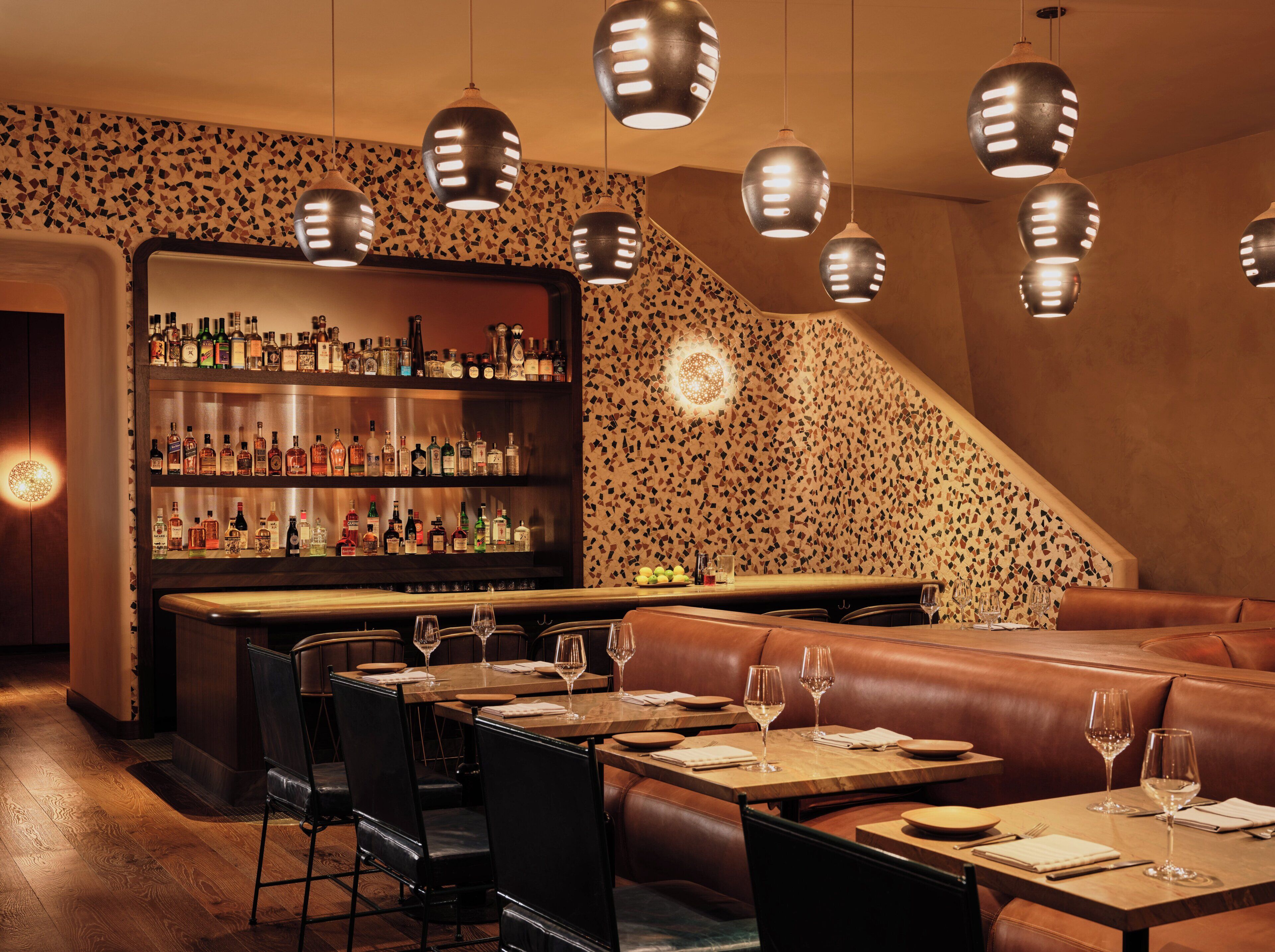 A bar area with a liquor display, leather seating, and pendant lighting.