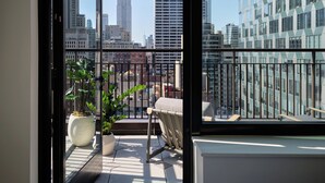 Un balcón con vistas al Empire State Building, una planta en maceta y una silla.