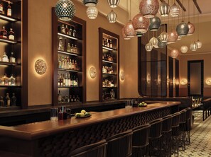 Uma área de bar com prateleiras cheias de garrafas de bebidas, luzes decorativas penduradas e um balcão comprido com banquetas.