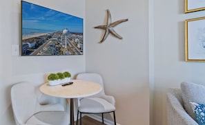 A room with a round table, two chairs, a starfish decoration, a framed picture, and a plant on the table. - 1 Bedroom Oceanfront - Walk right out to the beach! (Ocean Isle Beach)