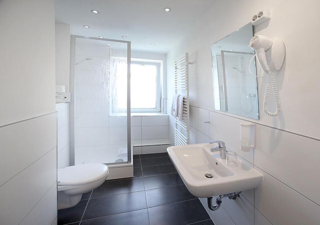 Een moderne badkamer met toilet, douche en wastafel.