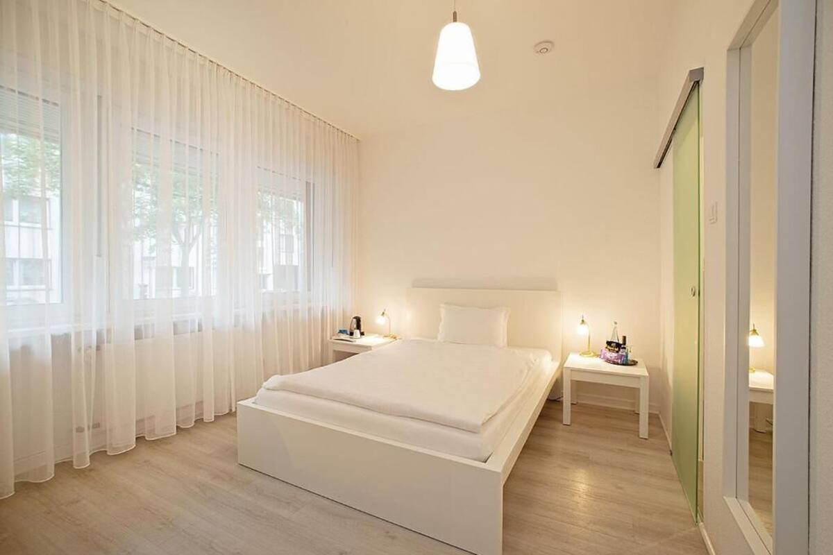A modern bedroom with a large bed, bedside tables, and a wardrobe.